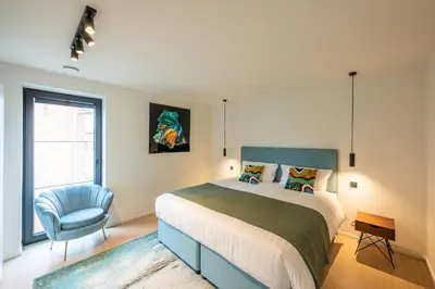 a bedroom with a bed and a blue chair at unique hideaway, holiday house with large garden in Kortenaken