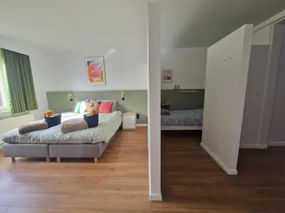 a living room with a bed and a room with a bed sqor at Parkvilla Vakantiehuis voor 23 personen in Heusden - Zolder