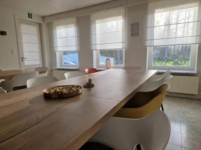 a dining room with a large wooden table and chairs at Parkvilla Vakantiehuis voor 23 personen in Heusden - Zolder