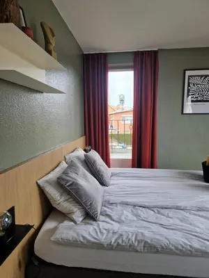 a bedroom with a bed with pillows and a window at Parkvilla Vakantiehuis voor 23 personen in Heusden - Zolder