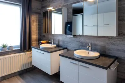 a bathroom with two sinks and a large mirror at Parkvilla Vakantiehuis voor 23 personen in Heusden - Zolder