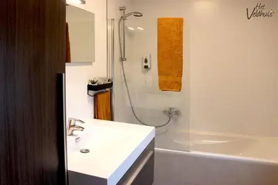 a white bathroom with a sink and a shower at Het Veldhuis in As
