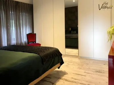 a bedroom with a bed and two red chairs at Het Veldhuis in As