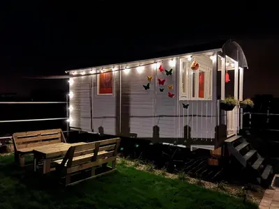 a small white house with lights on it at night at Ontwaken tussen de paarden in Helen-Bos